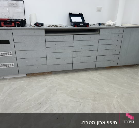 ארון כלים אפור עם מגירות רבות על רצפת שיש
